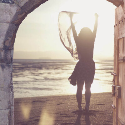 Woman on beach at sunset photographed through old open door