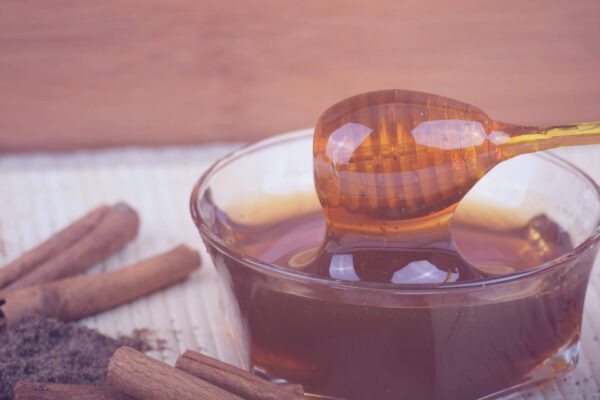 Glass with honey, round wooden spatula with honey