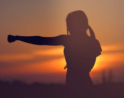 Woman in karate position at sunrise