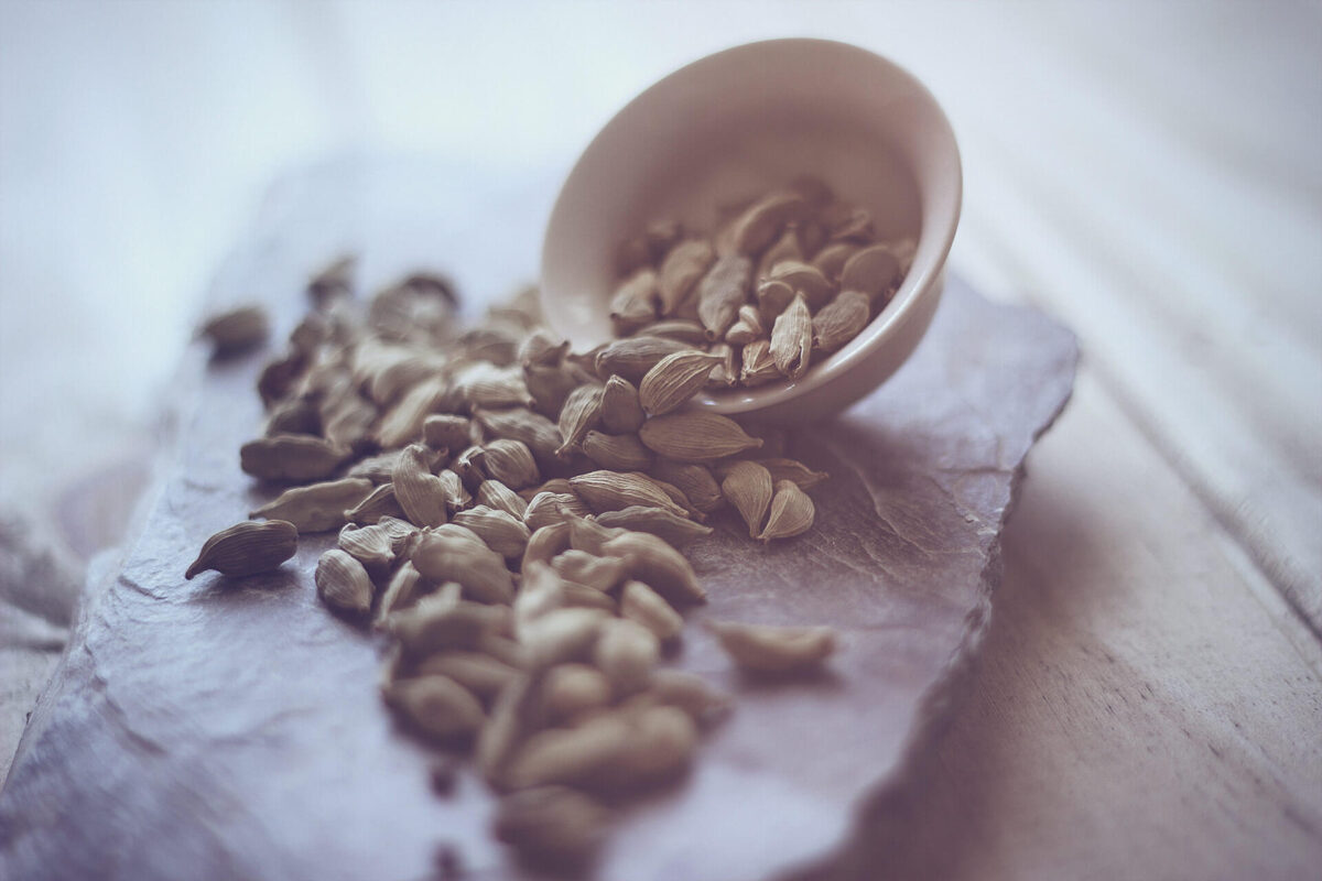Cardamom seeds on stone with small bowl