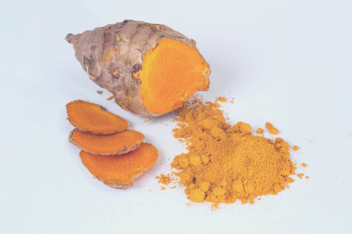 Sliced turmeric root on a white background, three slices of turmeric, turmeric powder in the foreground